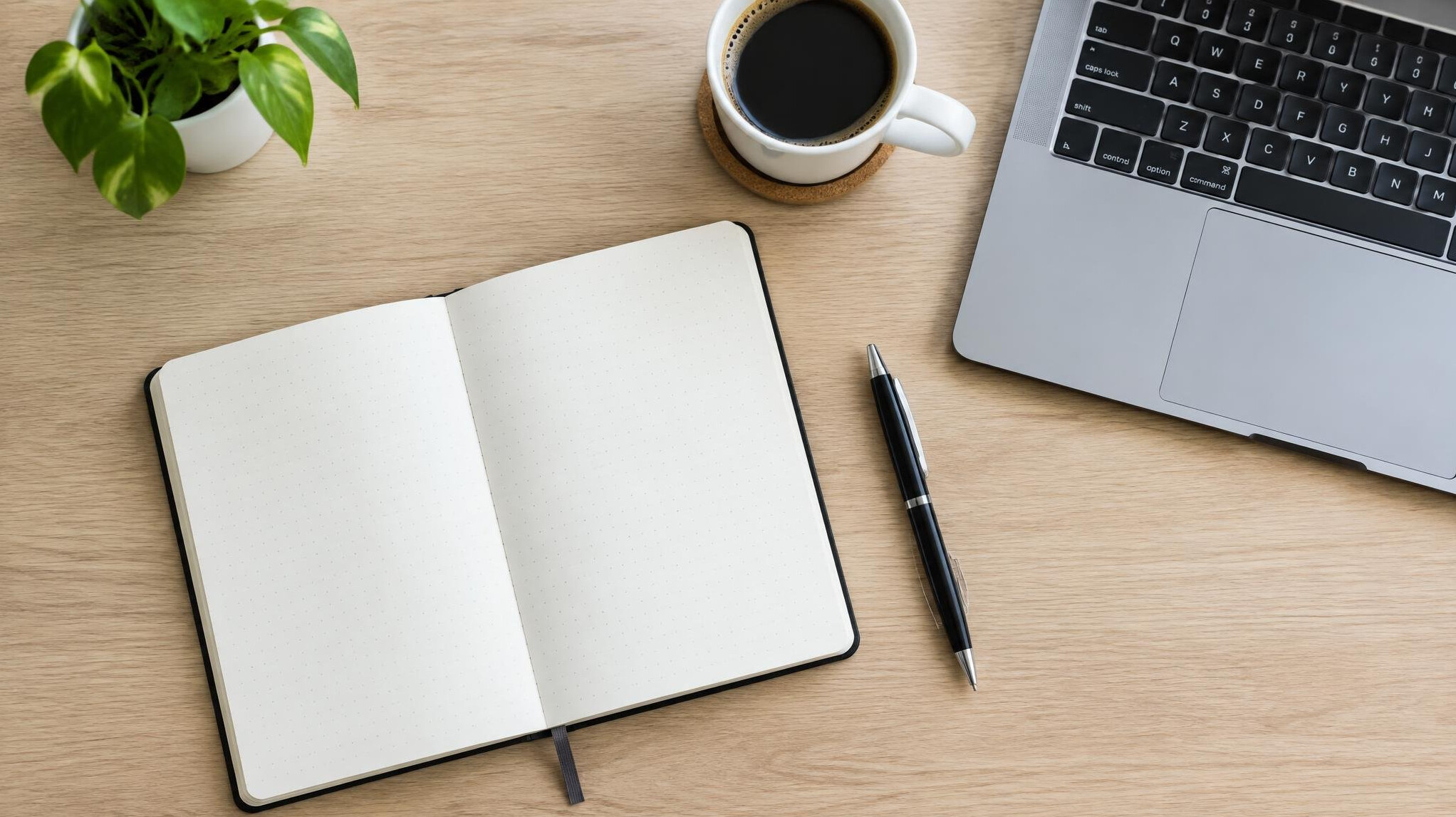 Desk with notebook, laptop and coffee cup from above
