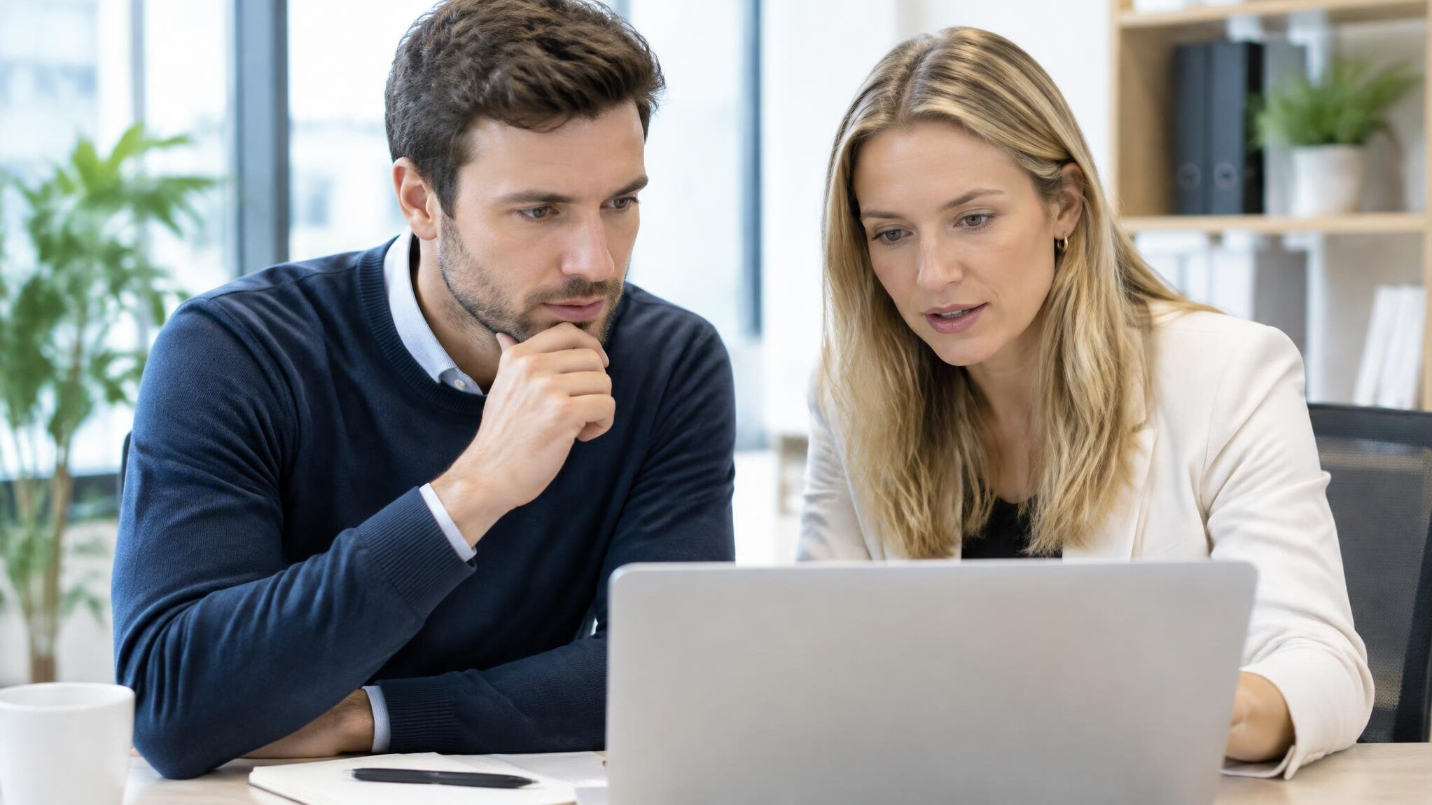 Two colleagues reviewing notes on a laptop